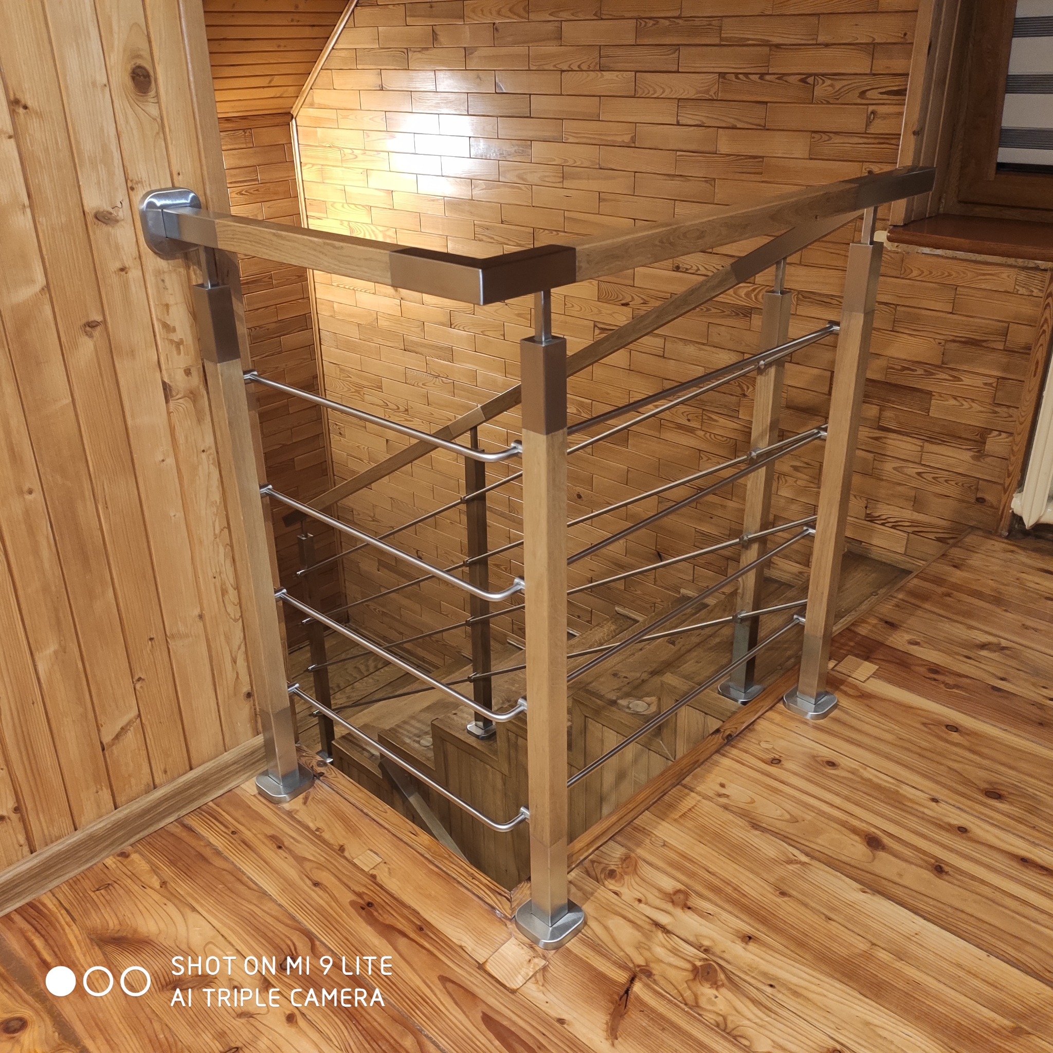 Drewniane schody z metalową balustradą z drewnianą poręczą, widok z góry, naturalne oświetlenie.