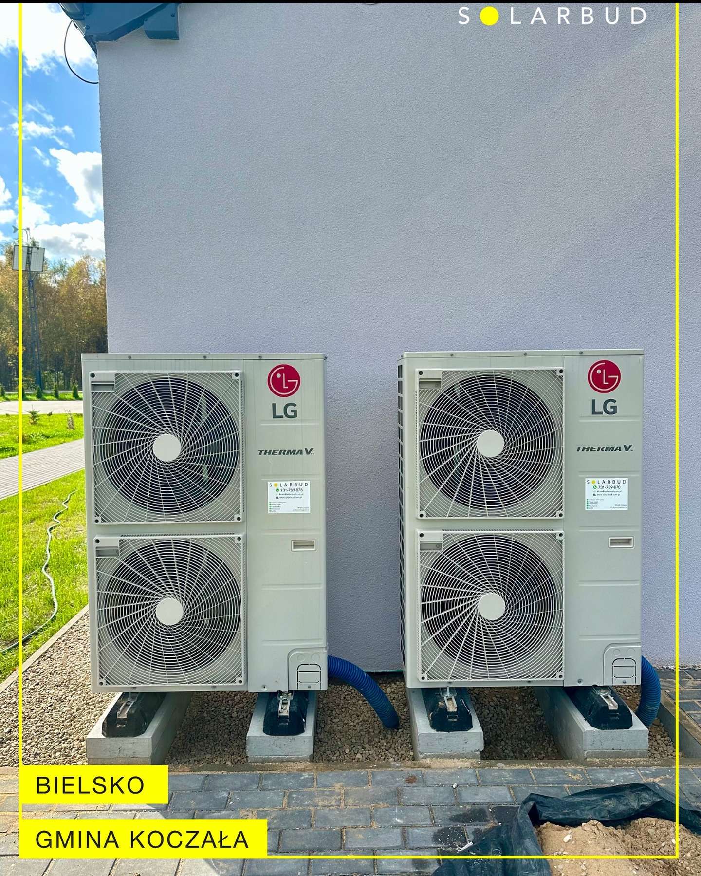 Dwie jednostki zewnętrzne pompy ciepła LG Therma V, zamontowane na betonowych podstawach przy szarej ścianie budynku. Widoczne niebieskie rury i otoczenie z kamyków.
