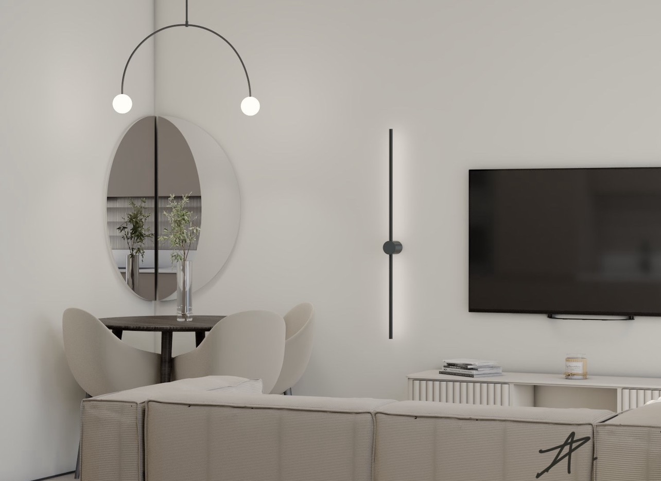 Minimalistyczny salon z okrągłym lustrem, nowoczesną lampą ścienną i telewizorem, utrzymany w jasnej kolorystyce.