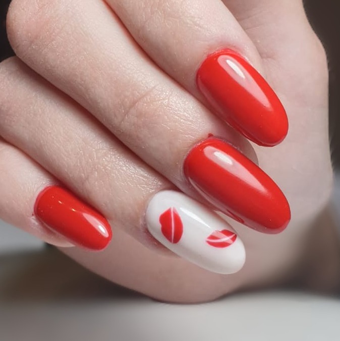 Czerwone, błyszczące paznokcie z motywem ust na białym tle, wykonane w Rawie Mazowieckiej.
