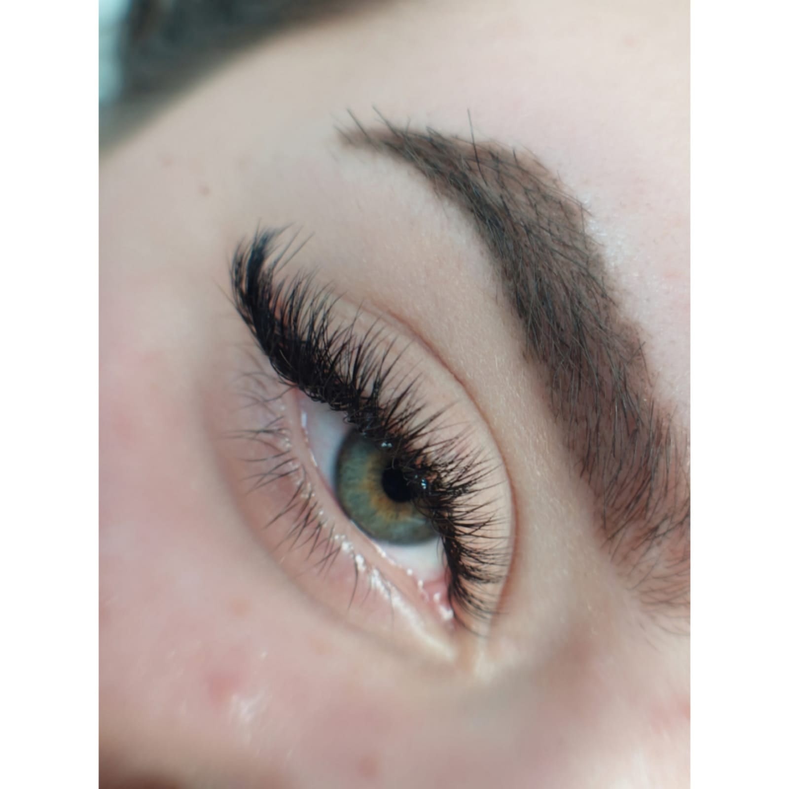 Zbliżenie na oko z gęstymi, czarnymi przedłużanymi rzęsami i naturalnie wyglądającą brwią.