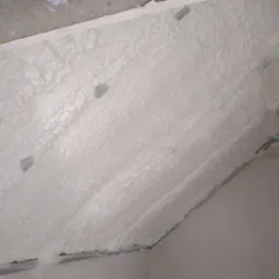 Poddasze z widoczną warstwą ocieplenia wykonaną z białej pianki poliuretanowej, mocowaną za pomocą metalowych kotew.