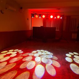 DJ Dandus - Daniel Piekarczyk Usługi Muzyczne - Czerwone oświetlenie sceniczne z reflektorami tworzącymi wzory na parkiecie w Mszanie Dolnej, przygotowane do imprezy.