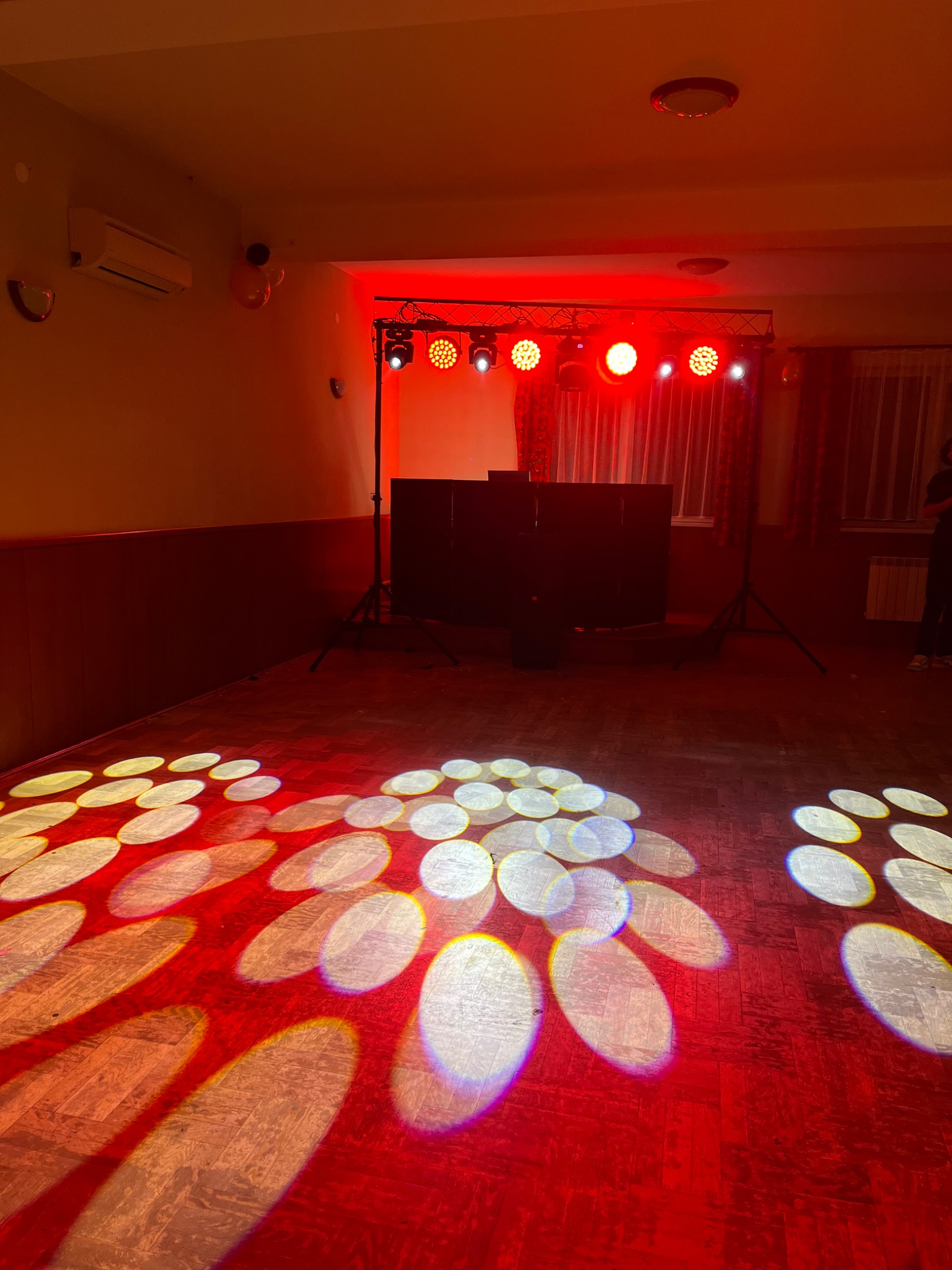 Czerwone oświetlenie sceniczne z reflektorami tworzącymi wzory na parkiecie w Mszanie Dolnej, przygotowane do imprezy.