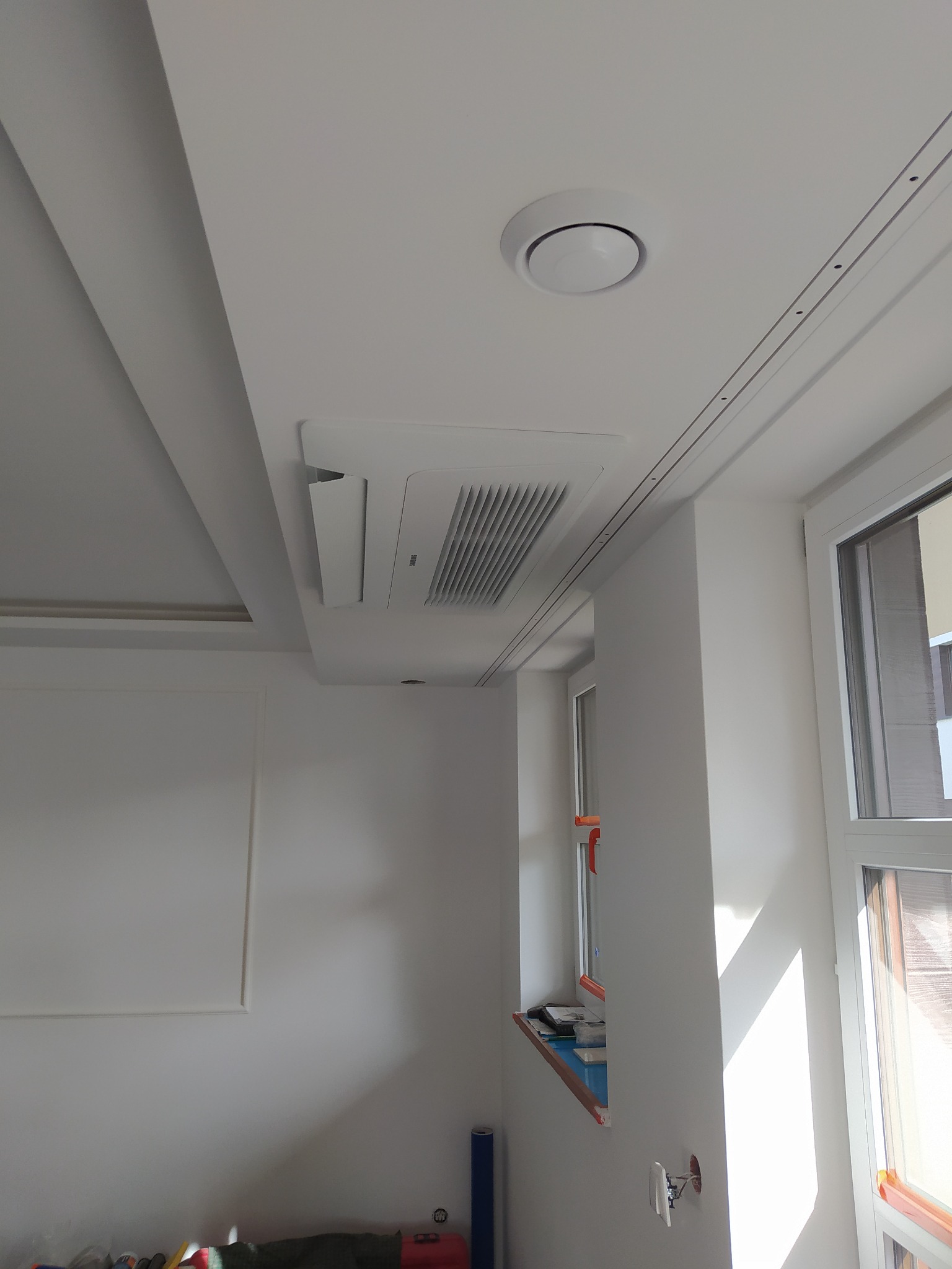 Sufitowa jednostka klimatyzacyjna Samsung w jasnym pomieszczeniu w Lublinie, widoczny okrągły nawiewnik i fragment okna.