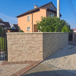 Firma Usługowa 3K - Nowoczesny, niski murek ogrodzeniowy z kamienia elewacyjnego w kolorze beżowym, oddzielający posesję od chodnika; widoczna brama wjazdowa i skrzynka na listy.