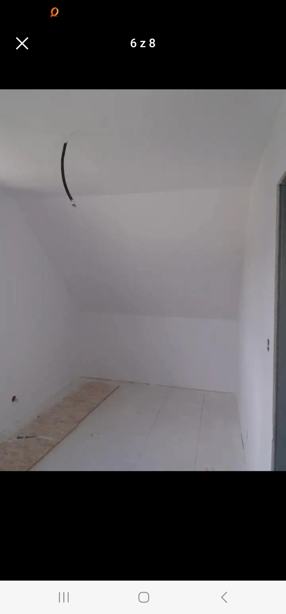 Świeżo pomalowane, jasne poddasze ze skośnym sufitem, widoczny fragment surowej płyty podłogowej oraz wystający przewód elektryczny.