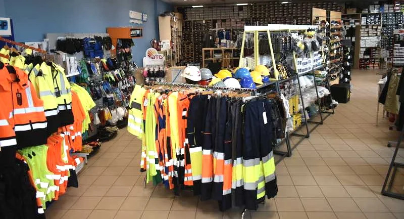 Wnętrze sklepu w Rzeszowie z odzieżą roboczą i ochronną, w tym kurtki, kamizelki odblaskowe i kaski.