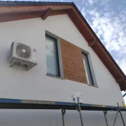 Ocieplona i pomalowana elewacja domu jednorodzinnego z widocznym klimatyzatorem, drewnianą okładziną elewacyjną, fragmentem rusztowania i wiadrem z farbą.