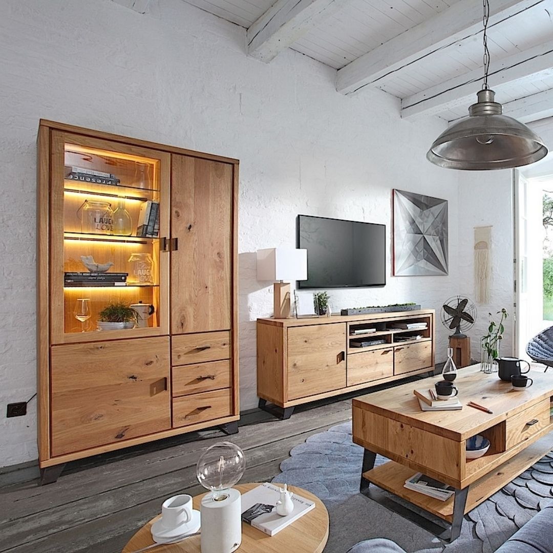 Jasne drewniane meble w salonie z oświetlonym kredensem, lampą wiszącą w stylu industrialnym i dekoracjami.