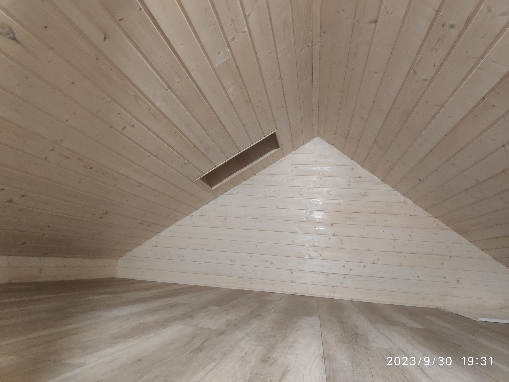 Drewniane panele boazeryjne na poddaszu w Redzie, widoczny otwór wentylacyjny w skosie sufitu, podłoga wykończona panelami imitującymi drewno, ujęcie z dołu.