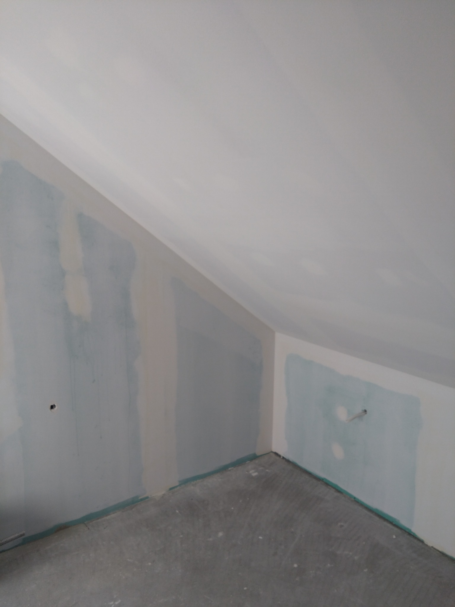 Poddasze z ukośnym sufitem po montażu płyt kartonowo-gipsowych, widoczne szpachlowane łączenia i przygotowanie do malowania.