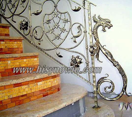 Kuta balustrada schodowa z motywem smoka na zakończeniu poręczy i dekoracyjnymi elementami roślinnymi na tle marmurowych schodów.