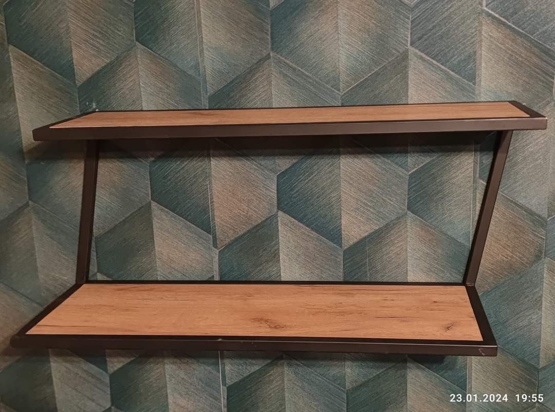 Dwu-poziomowa półka ścienna z drewnianymi blatami i metalową ramą, zamontowana na ścianie z geometryczną tapetą w odcieniach zieleni i szarości.