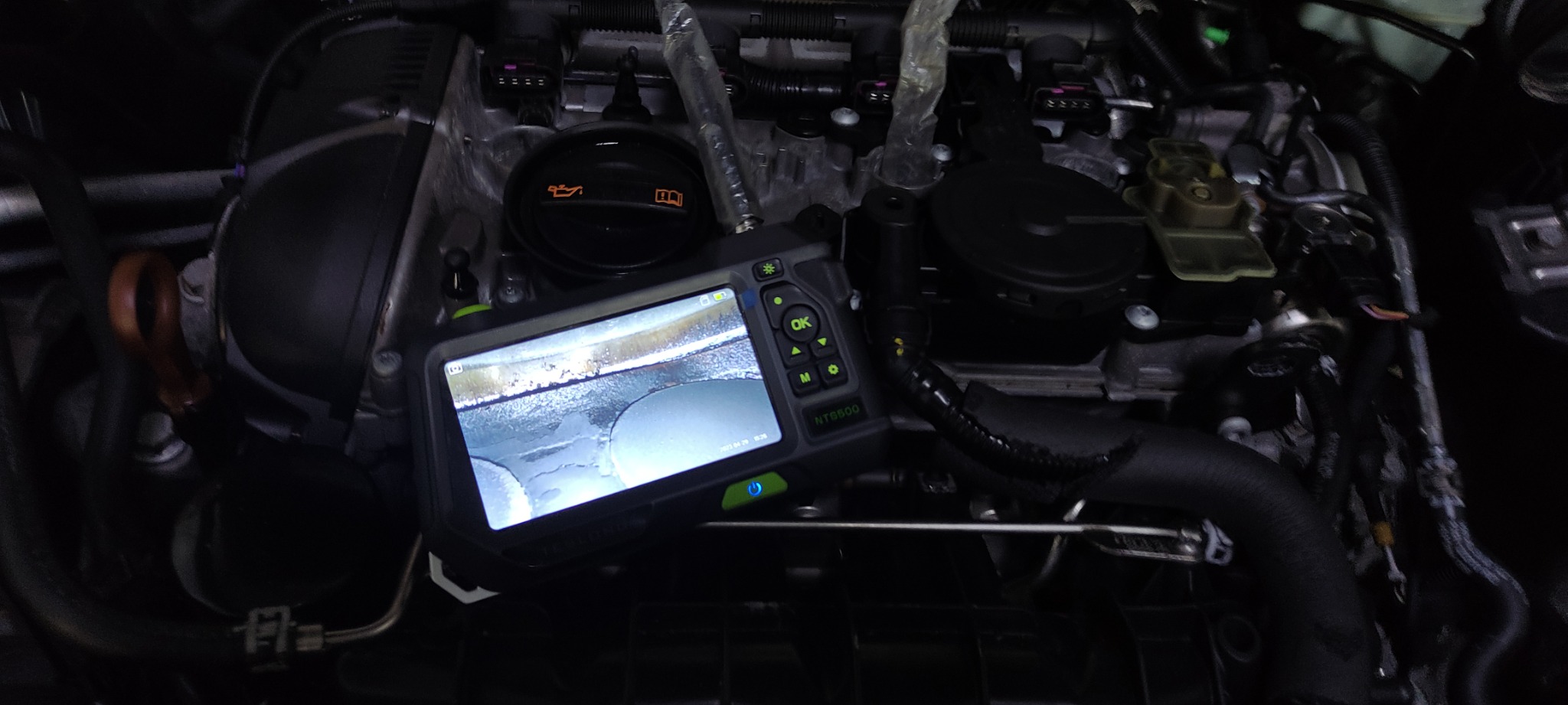 Diagnostyka cylindrów silnika samochodowego za pomocą endoskopu inspekcyjnego NTS500, widok na wyświetlaczu urządzenia przedstawia wnętrze cylindra z nagarem.