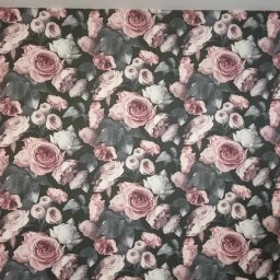 StabiBud.Art - Fragment ściany pokrytej tapetą w ciemnych kolorach z motywem róż i liści w odcieniach różu, bieli i szarości, widoczny fragment listwy przypodłogowej i profil głowy osoby pracującej.