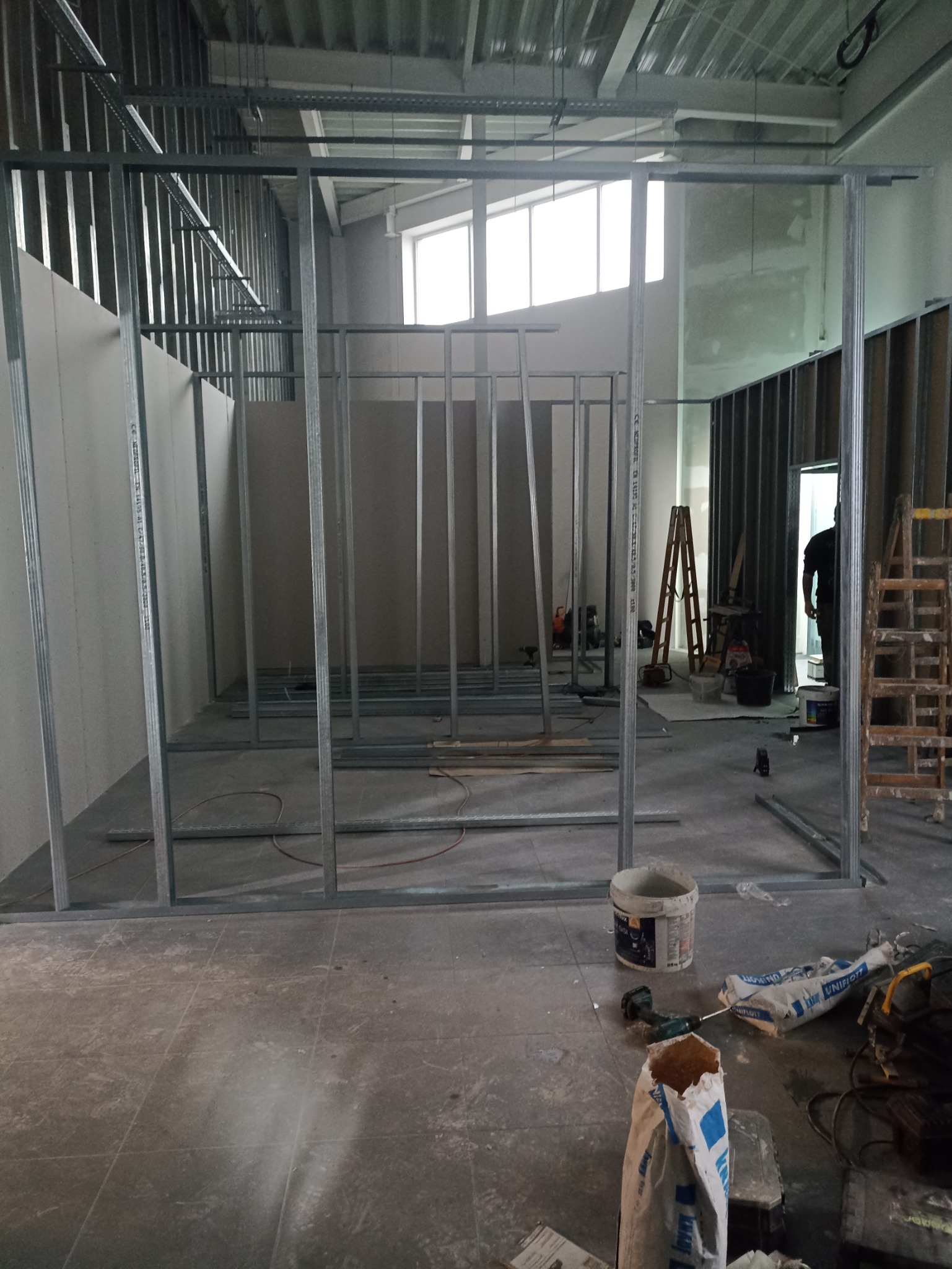 Konstrukcja szkieletowa z profili stalowych pod ścianę działową z płyt gipsowo-kartonowych w trakcie montażu w Opolu, widoczne narzędzia i materiały budowlane na podłodze.