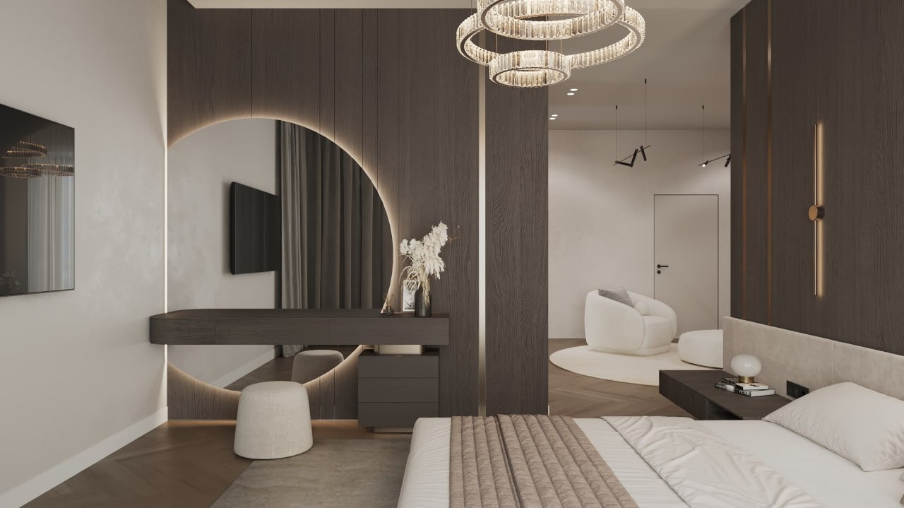 Nowoczesna sypialnia z toaletką z podświetlanym lustrem w kształcie półksiężyca, łóżkiem z beżową narzutą i widokiem na pokój dzienny z białym fotelem.