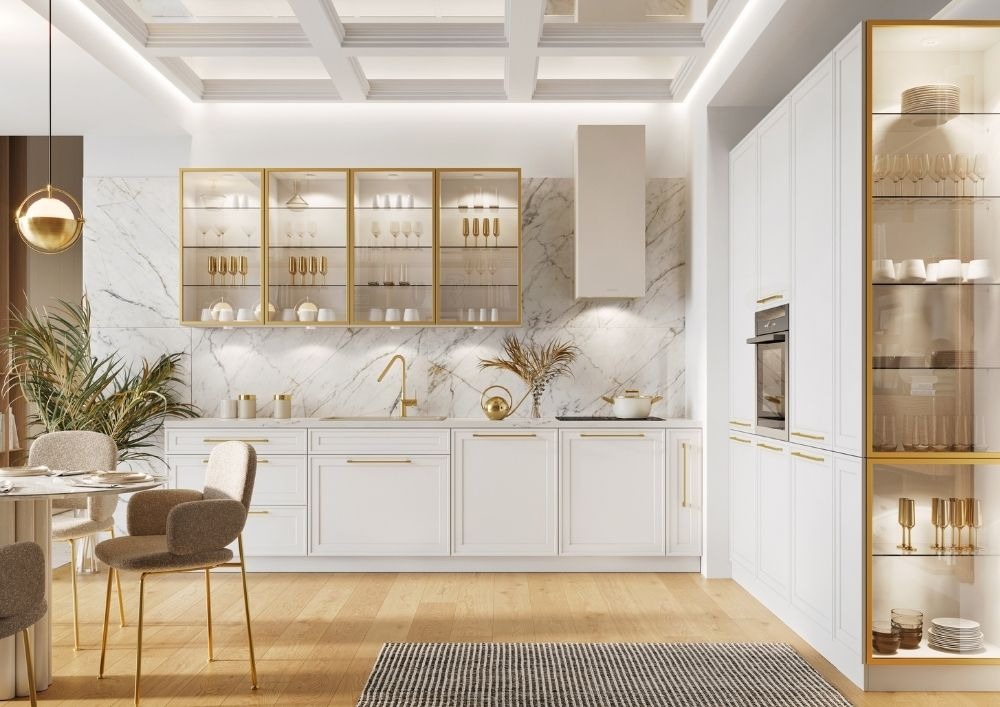 Elegancka, biała kuchnia z marmurowym backsplashiem i złotymi akcentami w Pruszczu Gdańskim, wyposażona w przeszklone szafki wiszące i wysoki słupek z piekarnikiem.