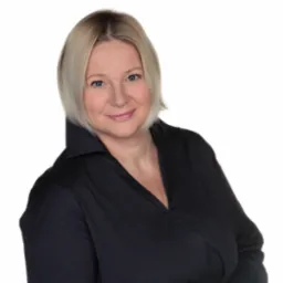 Portret uśmiechniętej kobiety z blond włosami w czarnej koszuli na białym tle.