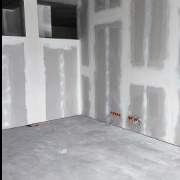 „DARO” Firma Remontowo - Wykończeniowa Dariusz Bąk - Surowe wnętrze w trakcie prac wykończeniowych: ściany z płyt karton-gips, widoczne puszki elektryczne, surowy betonowy strop. Minimalistyczny, industrialny charakter.