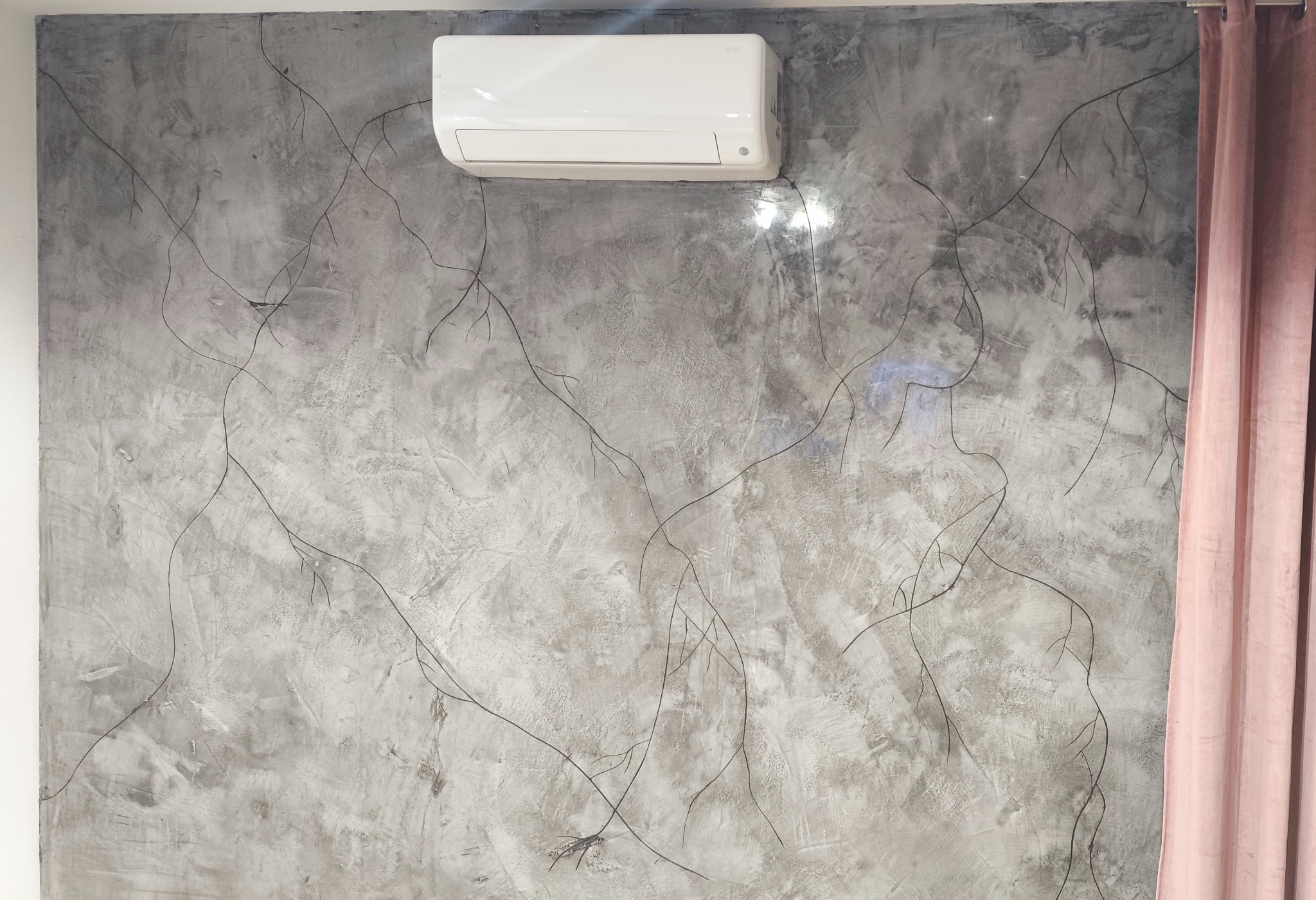 Betonowa ściana z dekoracyjnym wzorem gałązek i klimatyzacją. Fragment zasłony po prawej stronie. Nowoczesne wykończenie wnętrza.