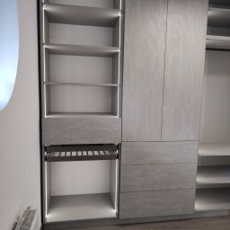 AWANGARDE - Szara szafa na wymiar z oświetleniem LED, otwartymi półkami i wysuwanym koszem na buty, widok z boku na tle podłogi z paneli.