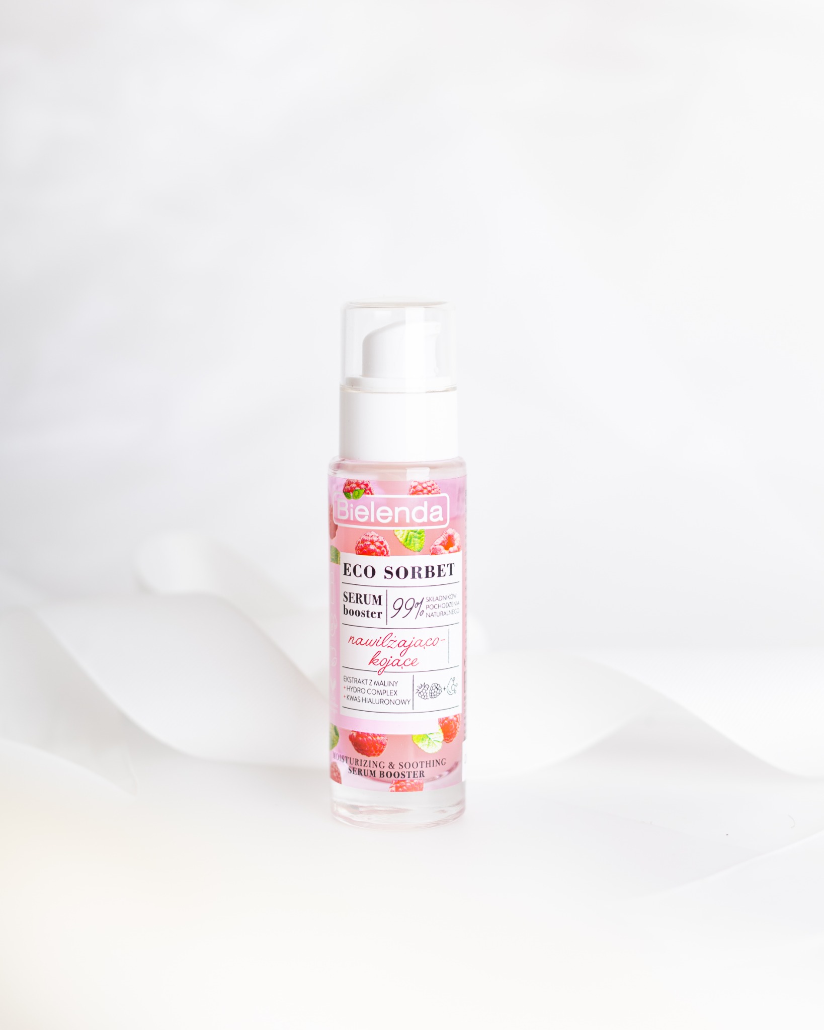 Butelka serum do twarzy Bielenda Eco Sorbet na białym tle z delikatnymi fałdami, z bliska, eksponująca etykietę z malinami i napisem 'nawilżająco-kojące'.