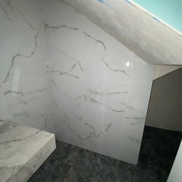 TILER Oleksandr Lebediev - Wykończona łazienka na poddaszu: białe płytki marmurowe na ścianach skośnych i szare płytki podłogowe. Widoczne łączenia płytek i surowy stan sufitu.