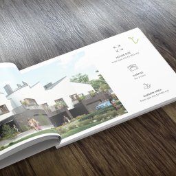 A2 studio - Otwarta broszura reklamowa leżąca na drewnianym stole prezentuje wizualizację osiedla domów jednorodzinnych z samochodami i zadbaną zielenią, zawierająca informacje o powierzchni domów, garaży...