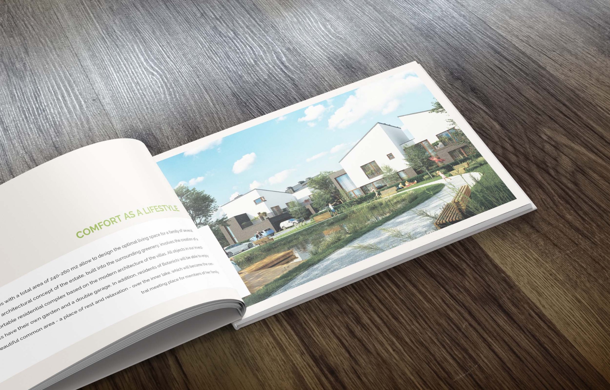 Otwarta broszura reklamowa leżąca na drewnianej powierzchni, prezentująca wizualizację nowoczesnego osiedla domów jednorodzinnych z zielenią i jeziorkiem.