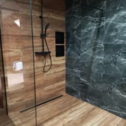 Nowoczesna kabina prysznicowa walk-in z czarną armaturą, wykończona płytkami imitującymi drewno i marmur, z odpływem liniowym w podłodze.