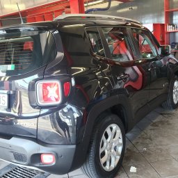 PIN UP CAR WASH SPÓŁKA Z OGRANICZONĄ ODPOWIEDZIALNOŚCIĄ - Czarny Jeep Renegade Limited, widok z tyłu, w trakcie czyszczenia w myjni; widoczny odkurzacz przemysłowy i mokra podłoga.
