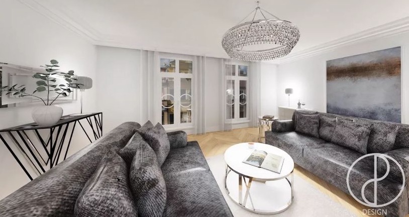 Wizualizacja salonu z dwoma szarymi sofami, okrągłym stolikiem kawowym, kryształowym żyrandolem i parkietem w jodełkę. Na ścianie abstrakcyjny obraz. Widoczne logo projektanta w prawym dolnym rogu.