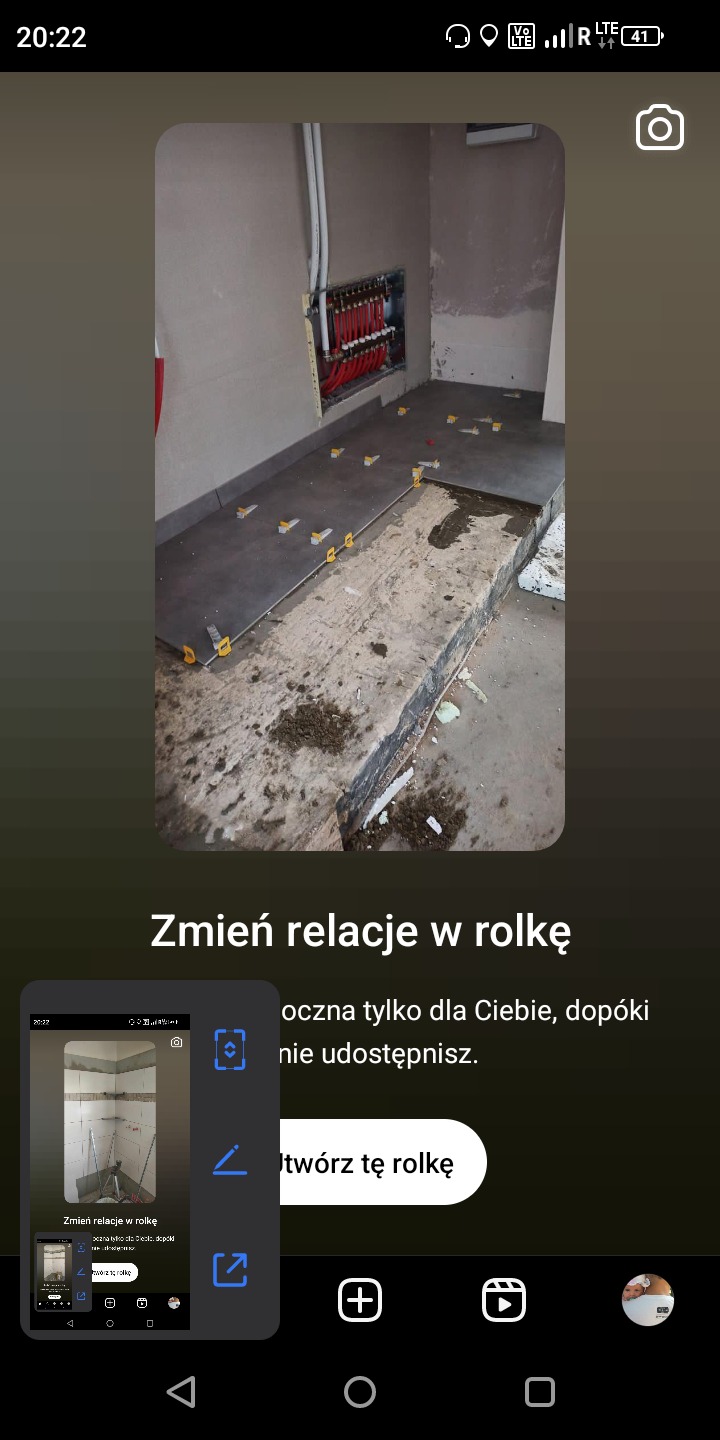 Fragment łazienki w trakcie układania płytek podłogowych; widoczne rury grzewcze w ścianie i plastikowe krzyżyki dystansowe między płytkami.