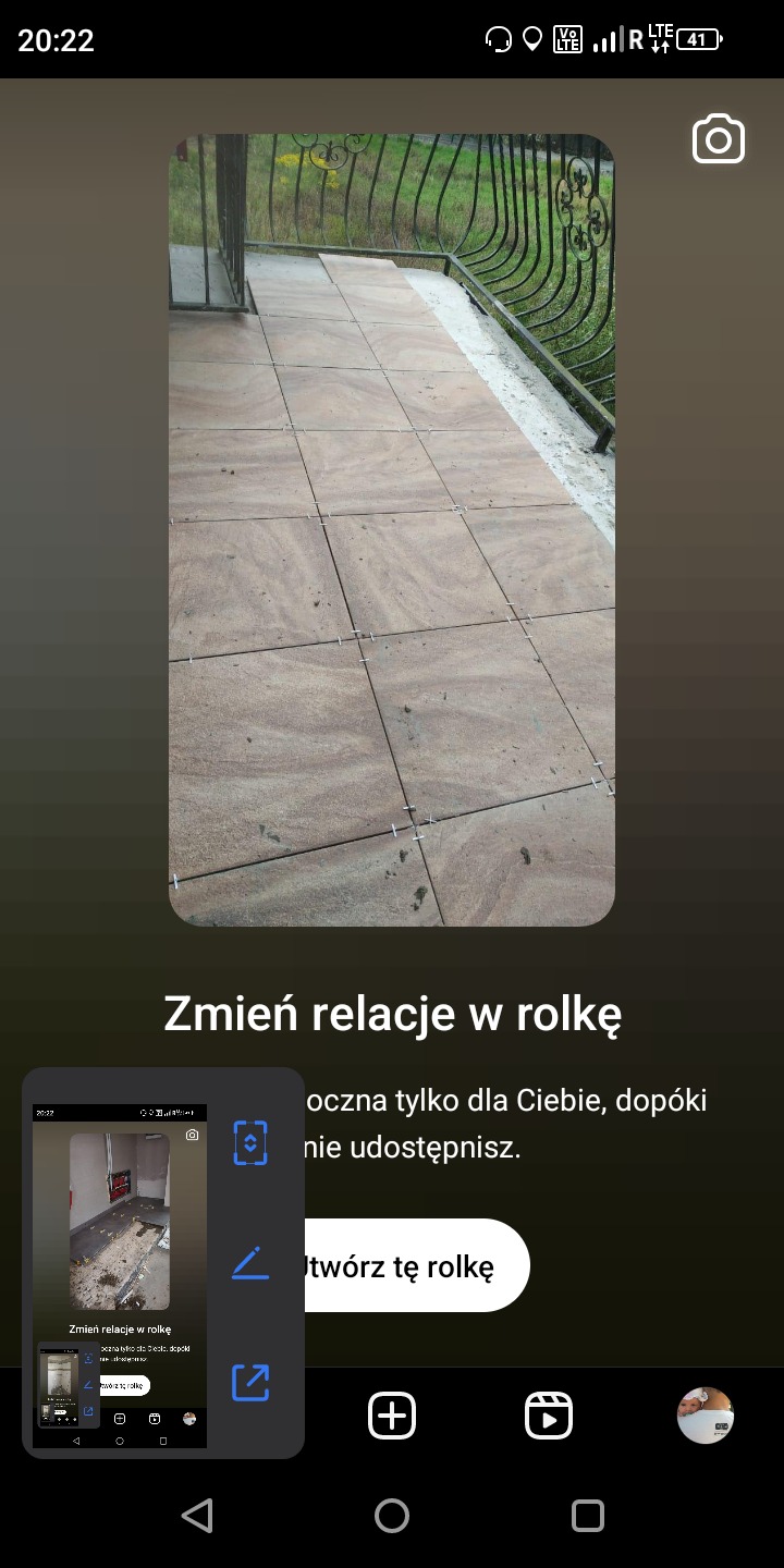 Balkon z brązowymi płytkami podłogowymi w trakcie układania, widoczne krzyżyki dystansowe, czarna metalowa balustrada z ozdobnymi elementami.