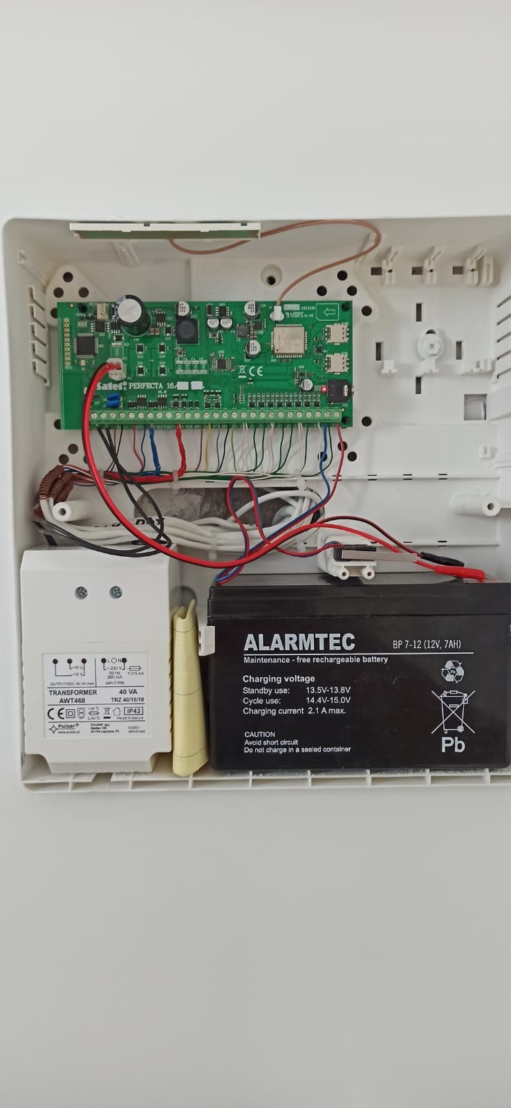 Wnętrze skrzynki alarmowej z elektroniką, transformatorem i akumulatorem alarmowym Alarmtec BP 7-12, zainstalowanej w Radomiu.