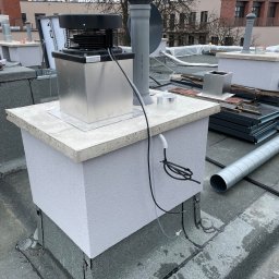 Wen-tech - Montaż rekuperacji na dachu budynku: widoczny centralny element rekuperatora z metalową obudową, rurami i przewodami, elementy wentylacyjne obok, dach pokryty papą.