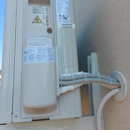 Wen-tech - Zewnętrzna jednostka klimatyzacji Haier zamontowana na ścianie budynku, widoczne przewody w peszlach wchodzące przez otwór w ścianie.