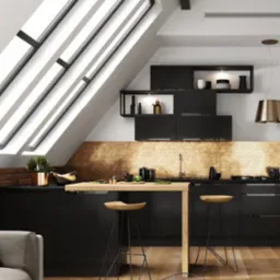 Czarna kuchnia na poddaszu ze złotą mozaiką na ścianie, drewnianym blatem i hokerami, oświetlona przez okno dachowe.