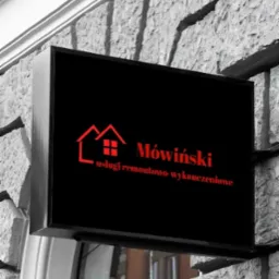 Szyld firmy remontowo-wykończeniowej Mówiński z logo w kształcie domu, zamontowany na kamiennej fasadzie budynku nad wejściem.