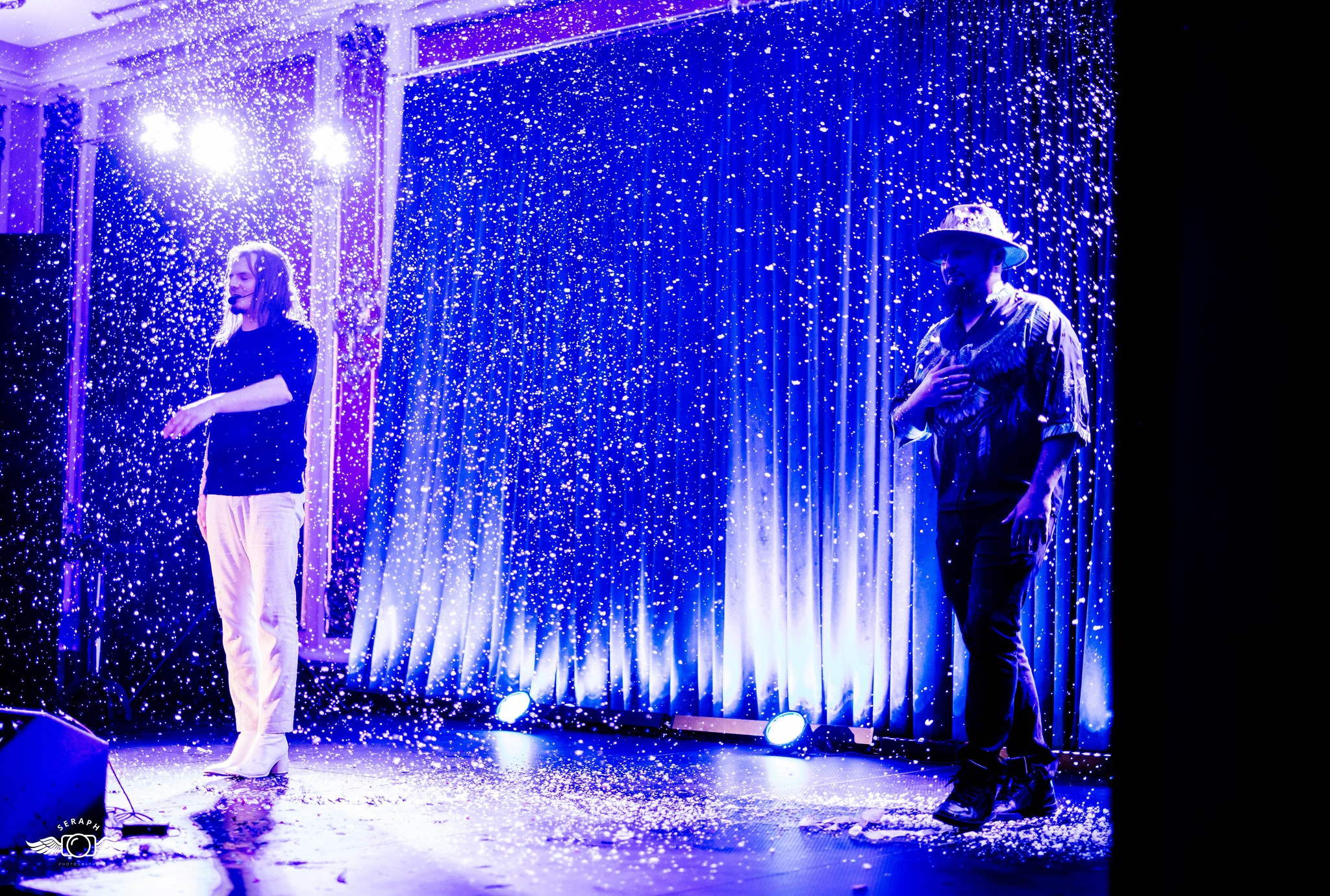 Dwóch mężczyzn na scenie w niebieskim oświetleniu, podczas występu z efektem padającego śniegu.
