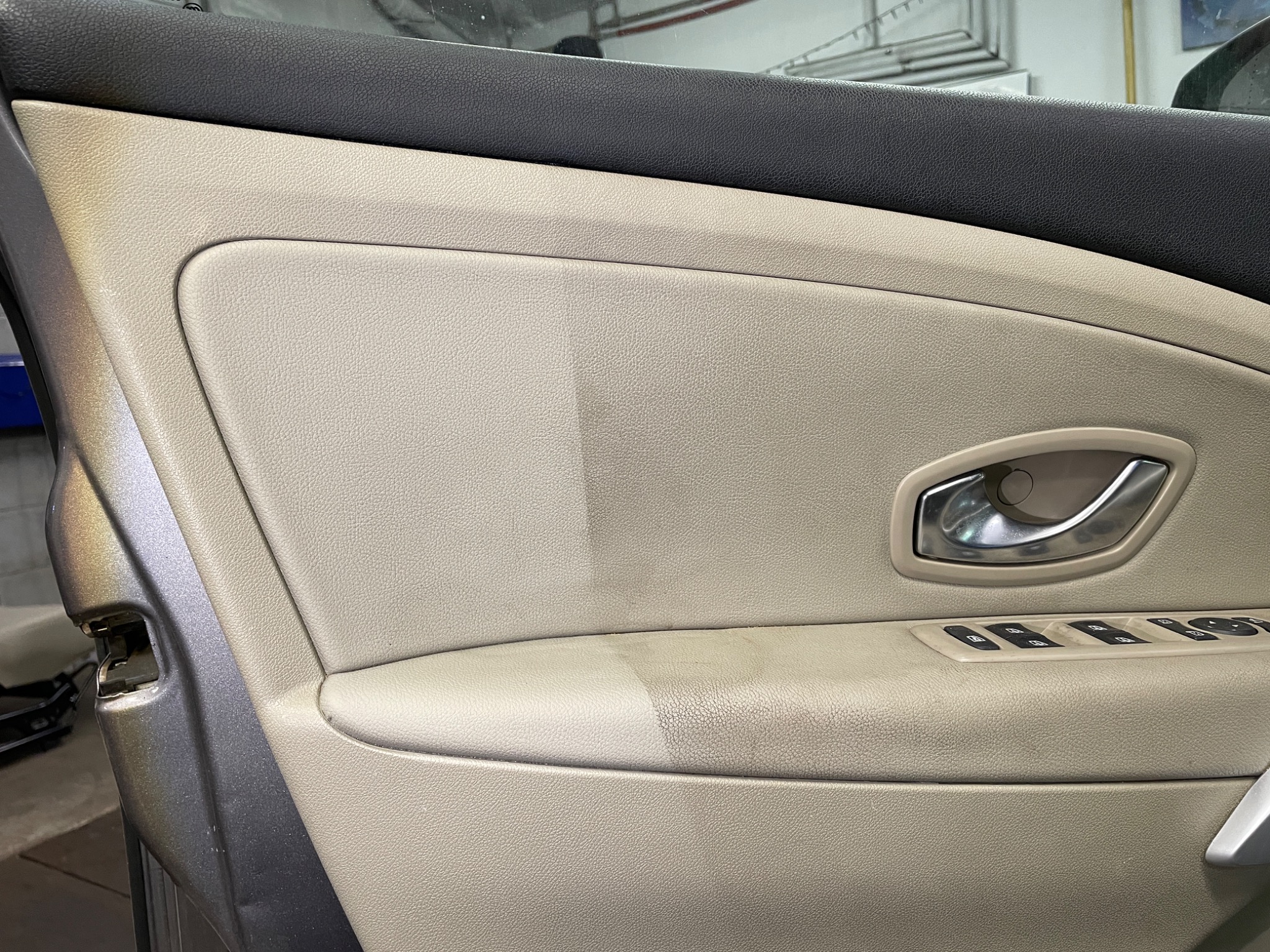 Częściowo wyczyszczone beżowe obicie drzwi samochodu w Katowicach, ukazujące różnicę przed i po praniu tapicerki samochodowej.