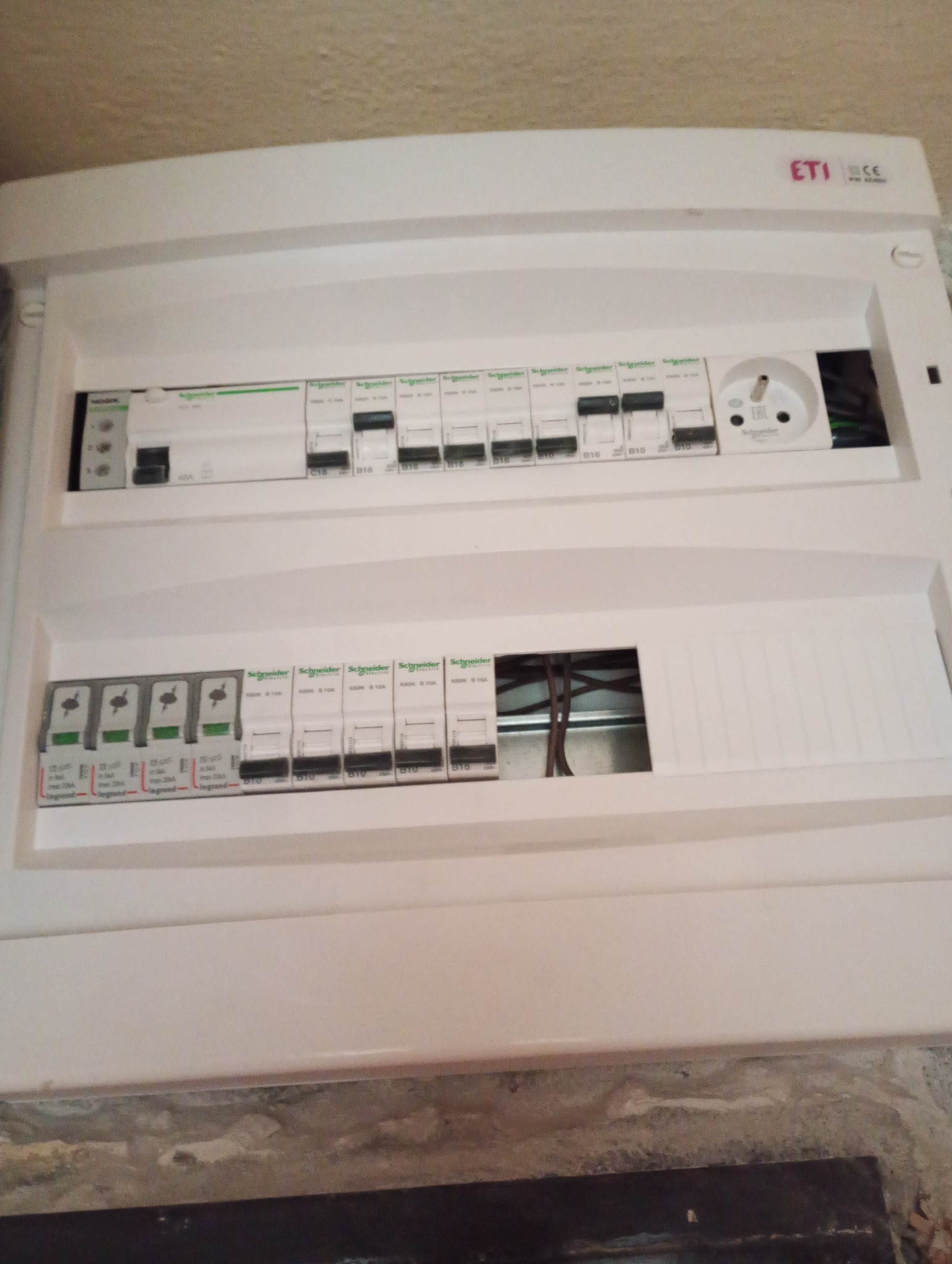 Rozdzielnia elektryczna ETI z bezpiecznikami Schneider i Legrand, widok z bliska na zainstalowane zabezpieczenia. Elementy instalacji elektrycznej.