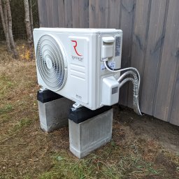 Jednostka zewnętrzna klimatyzatora Rotenso Revio RO35X R14. Agregat posadowiony na bloczkach fundamentowych, co eliminuje możliwość przenoszenia się drgań na drewnianą konstrukcję budynku.