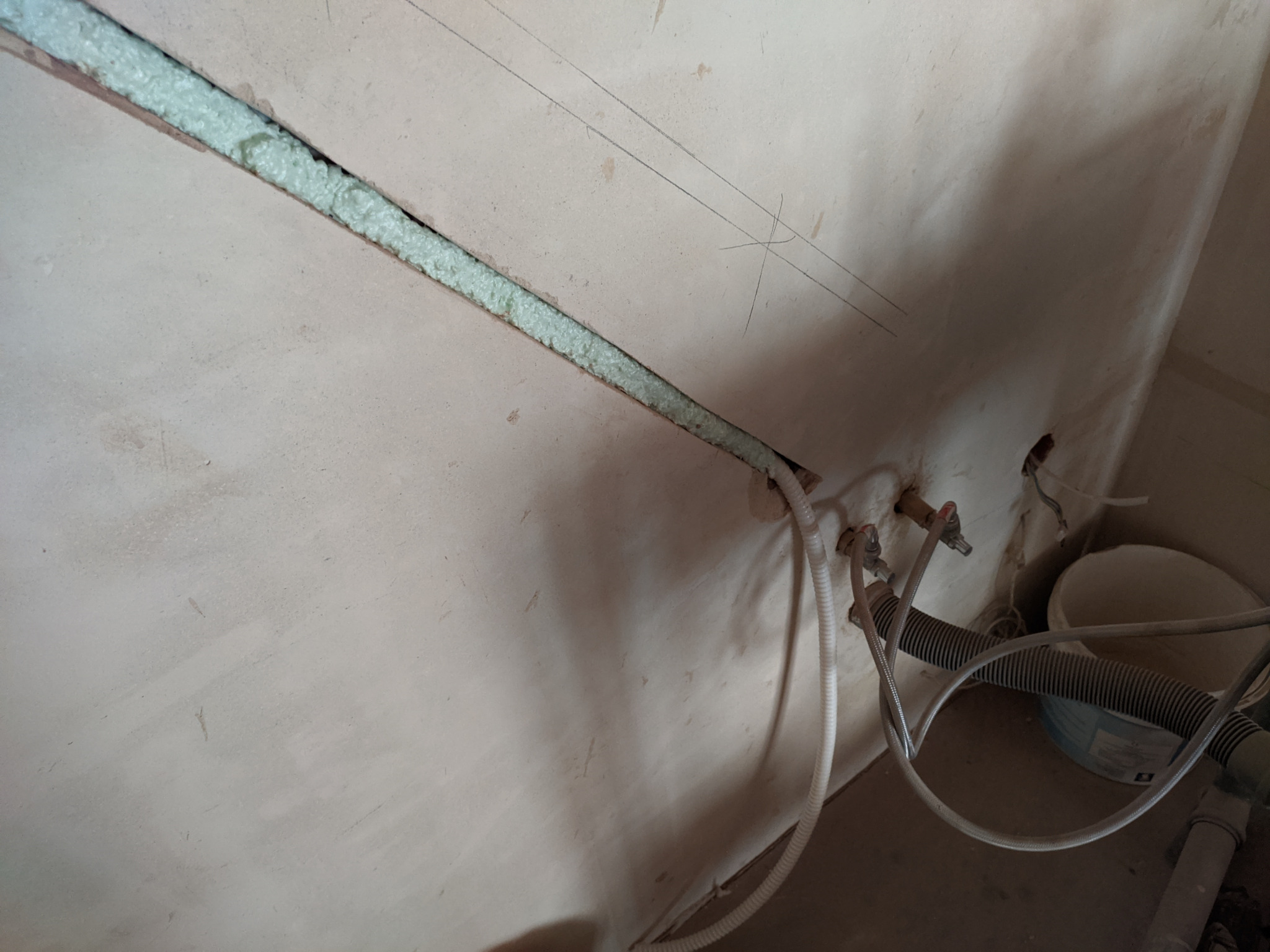 Instalacja rur i przewodów w ścianie w stanie deweloperskim, z widoczną pianką izolacyjną w bruździe, rurami miedzianymi i przewodami odprowadzającymi skropliny do kanalizacji, zarysowane linie...