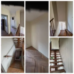 Klatka schodowa po odświeżeniu ścian kremową farbą, widoczne drewniane schody i parkiet w jodełkę, ściany pomalowane na jednolity kolor, brak listew przypodłogowych.