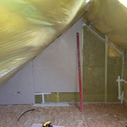 Adrian Sroka - Poddasze w trakcie adaptacji: ocieplenie wełną mineralną zabezpieczoną folią, montaż płyty karton-gips, poziomica oparta o ścianę, widoczne przewody elektryczne.