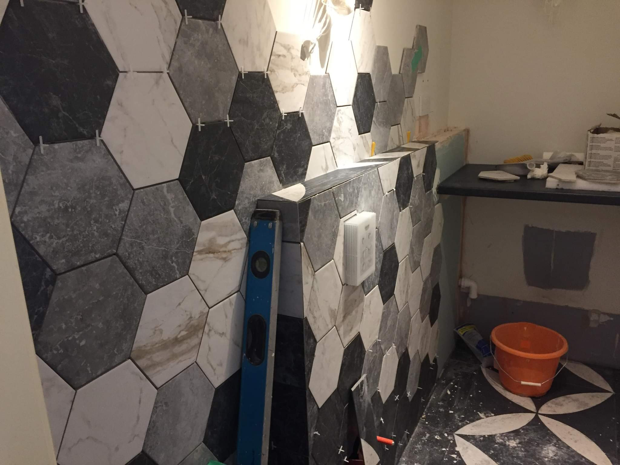 Układanie heksagonalnych płytek w odcieniach szarości i bieli w Skoczowie, widoczna poziomica i krzyżyki dystansowe.