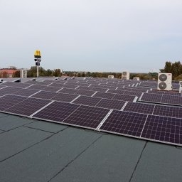TT Inwest - Rząd paneli słonecznych na płaskim dachu budynku z widocznymi jednostkami klimatyzacyjnymi i logo McDonald's w tle.